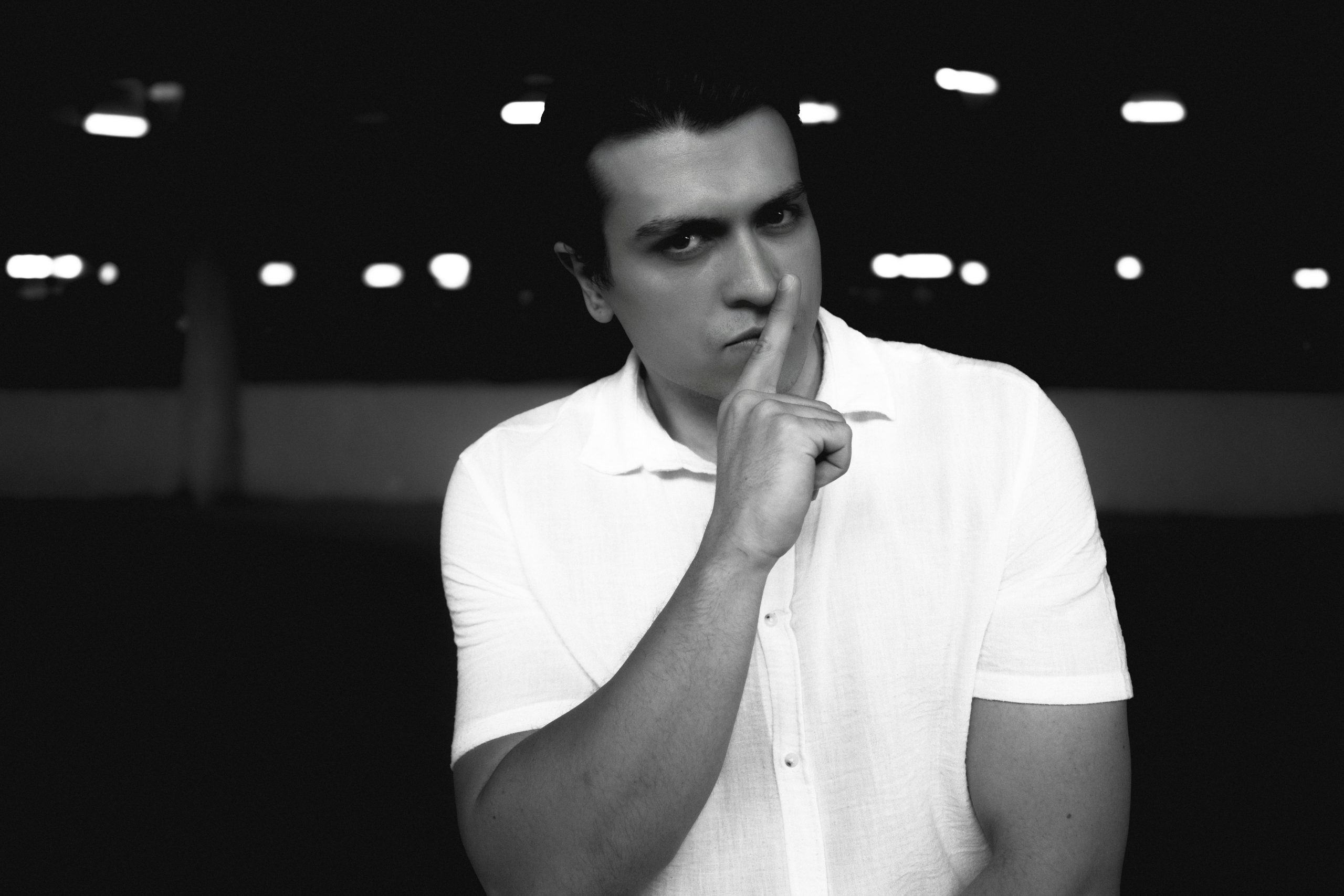 Black and white portrait of a man gesturing for silence, captured in Ankara.